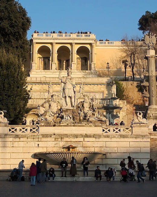 People gathering by the fountain in Piazza del Popolo, Roma, Italia.
