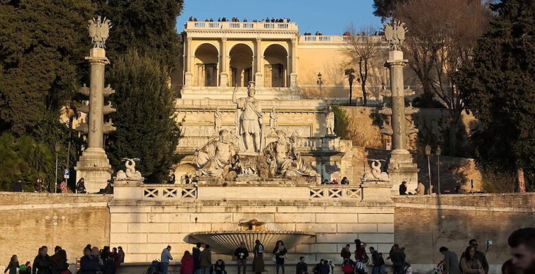 People gathering by the fountain in Piazza del Popolo, Roma, Italia.