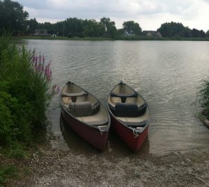Two canoes on the water at the edge of a beach.