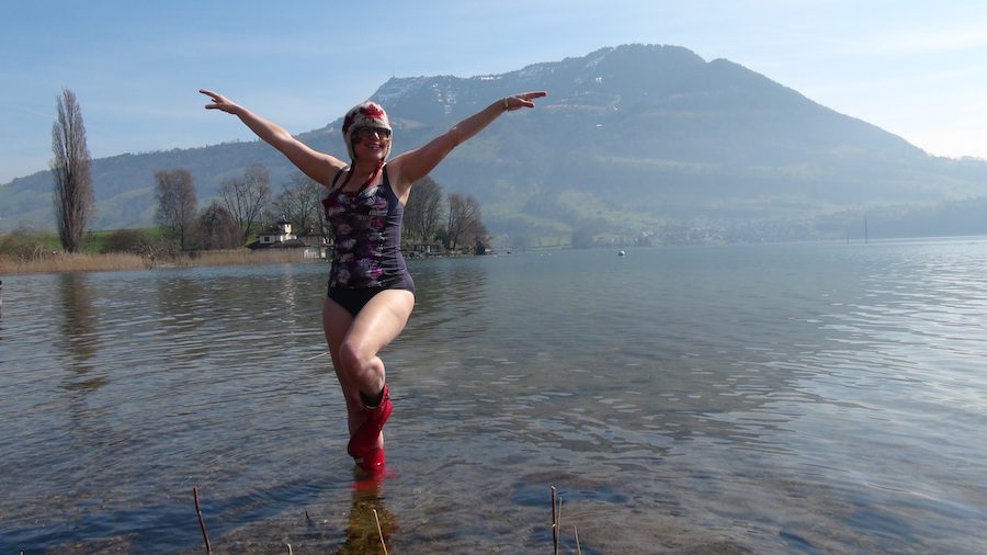 Erica doing a fun and silly swimsuit calendar girl style pose on a lake near Lucerne.