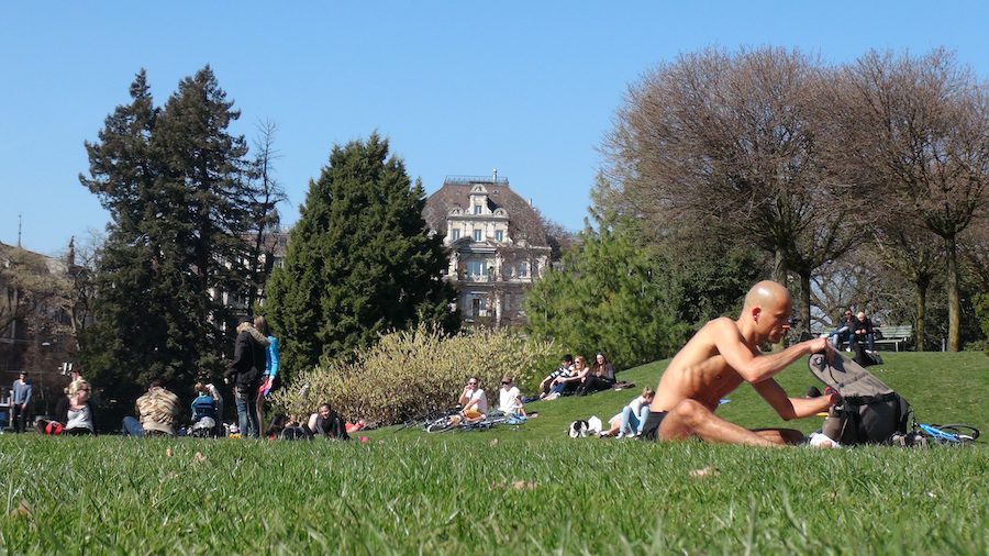 People enjoying the lawn in a public park, soaking in the Spring sun in Zurich.