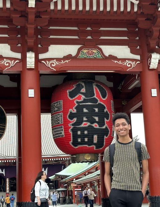 A young man standing in front of a temple in Japan.