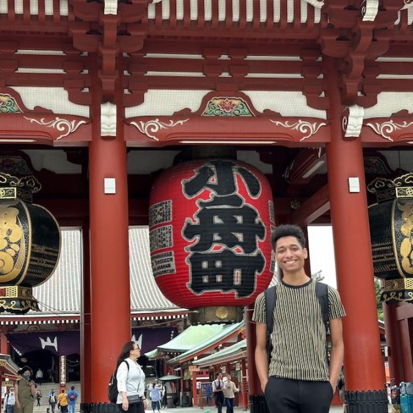 A young man standing in front of a temple in Japan.