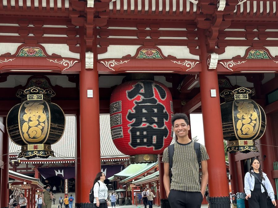 A young man standing in front of a temple in Japan.