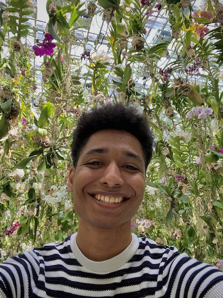 Smiling young man surrounded by flowers in the floating flower garden at teamLab Planets.
