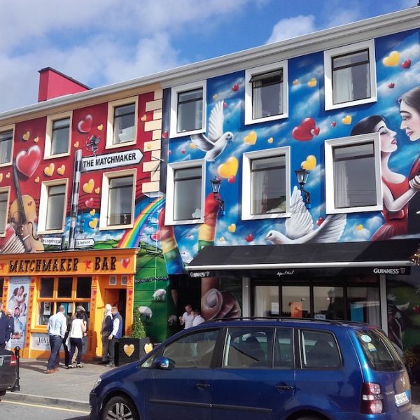 The colourfully painted exterior of The Matchmaker Bar in Lisdoonvarna, baring hearts and cupids with their bows drawn.