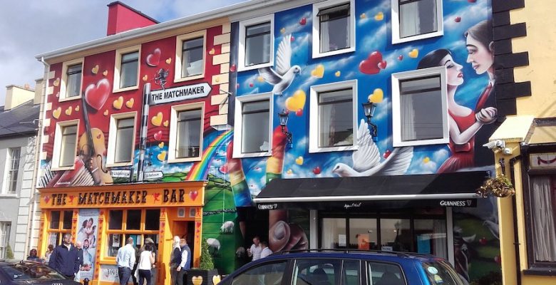 The colourfully painted exterior of The Matchmaker Bar in Lisdoonvarna, baring hearts and cupids with their bows drawn.