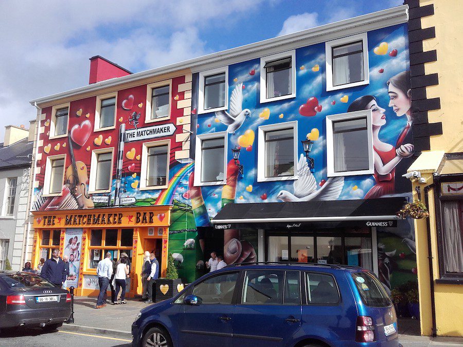 The colourfully painted exterior of The Matchmaker Bar in Lisdoonvarna, baring hearts and cupids with their bows drawn.