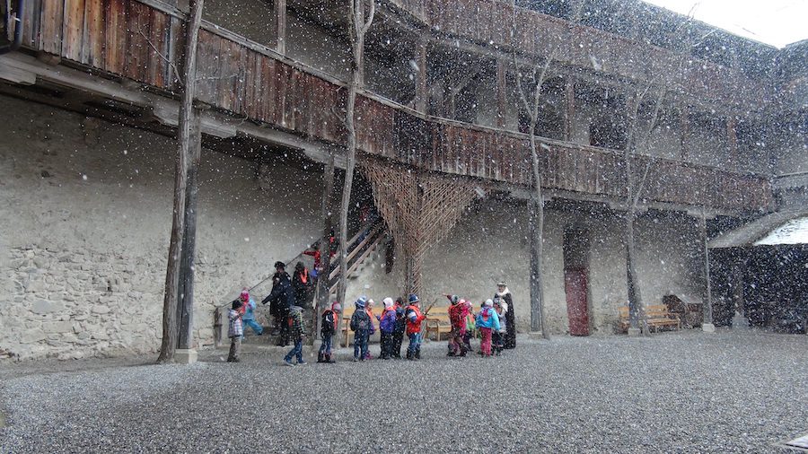 Snow falling on school kids in the courtyard at Gruyere Castle.