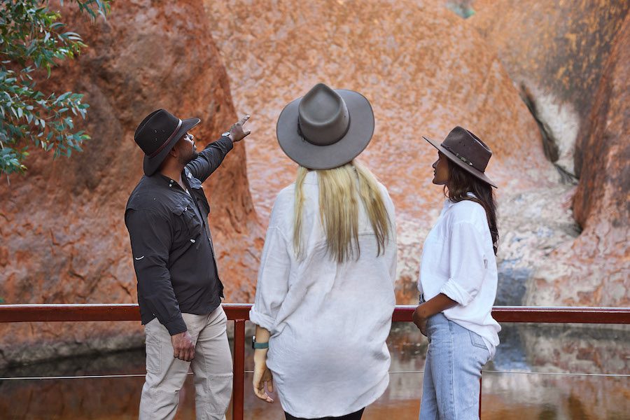A guide describes the Uluru watering hole, a source of water for human and animal inhabitants for thousands of years. Photo care of Voyages Indigenous Tourism Australia.