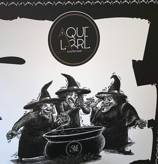 Aque Larre Gastro Pub sign featuring three witches, in Galicia, Spain.