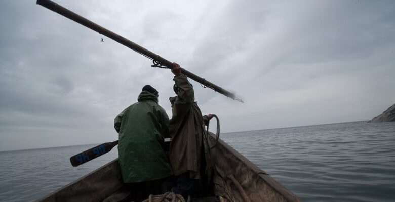 Fishermen hunting at sea with a spear.