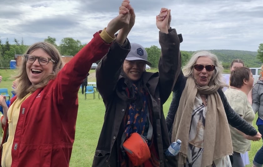 Erica Hargreave, Jacqueline Louie and Daphne March raising their arms up together with looks of joy on their faces.