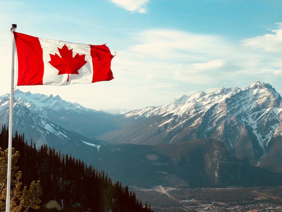 Canadian flag flying over the Rocky Mountains.