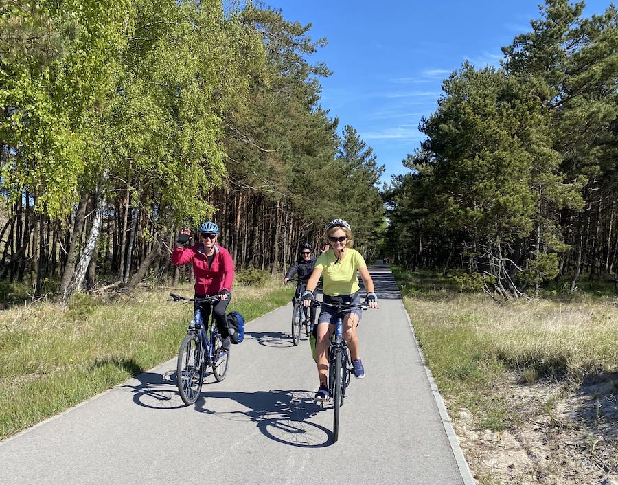 Fellow cyclists happily cycling through a forest in the Baltics with Exodus Adventure Travels.