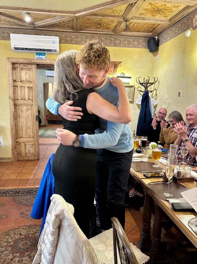 Lisa hugging Exodus Adventure Travels' Baltic cycling leader Andrius Mažrimas, while our cycling group seated at the dinner table, claps following thank you speech at the final dinner.