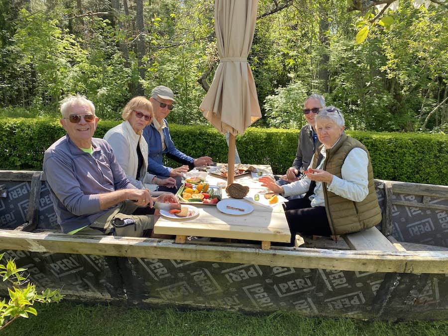 Fellow Exodus Adventure Travels cyclists enjoying a picnic of smoked fish in a wooden boat at Lithuanian fisherman’s homestead.