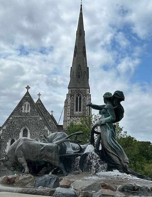 Goddess and oxen statue in the fountain with St. Alban's Church in behind.