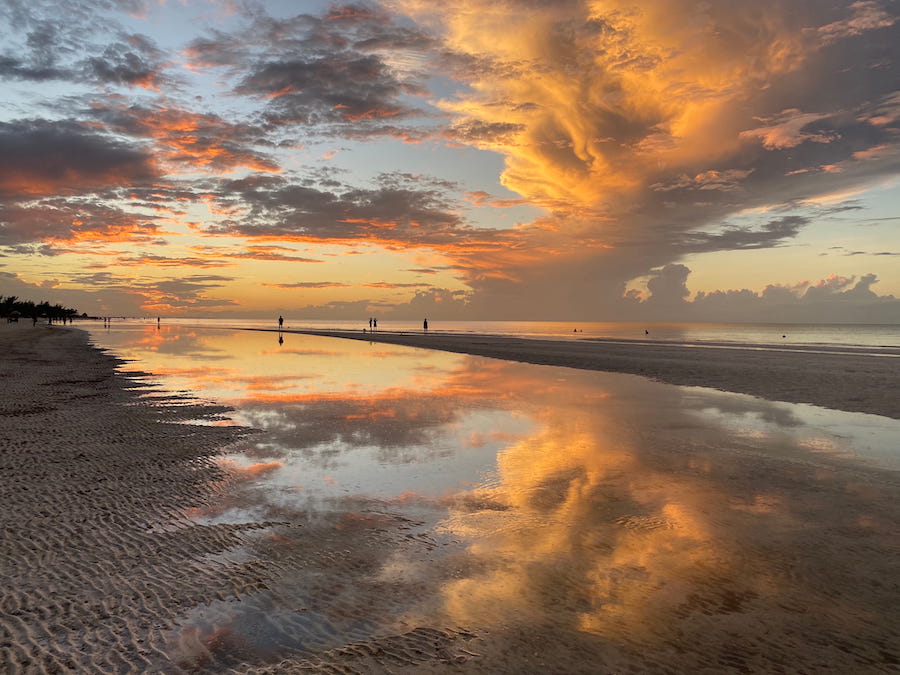 The painted sky and reflection of an Isla Holbox sunset along the beach.