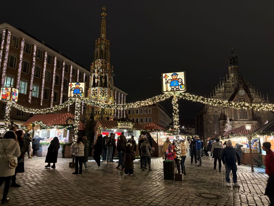 Visitor peruse the stalls, enjoying the elegant lights of the Nuremberg Chriskindlmarkt at night.