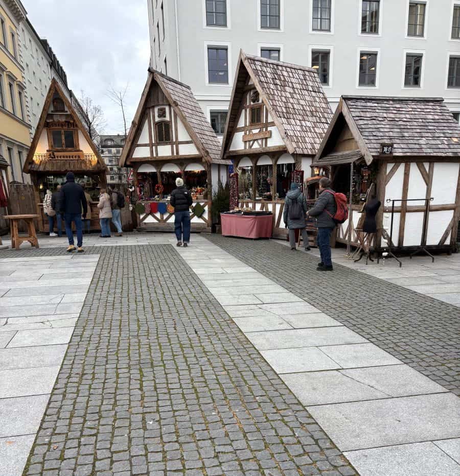 Winter wardrobe clad people checking out the cute, Hansel and Gretel like house stalls at the Munich Medieval Christmas Market.