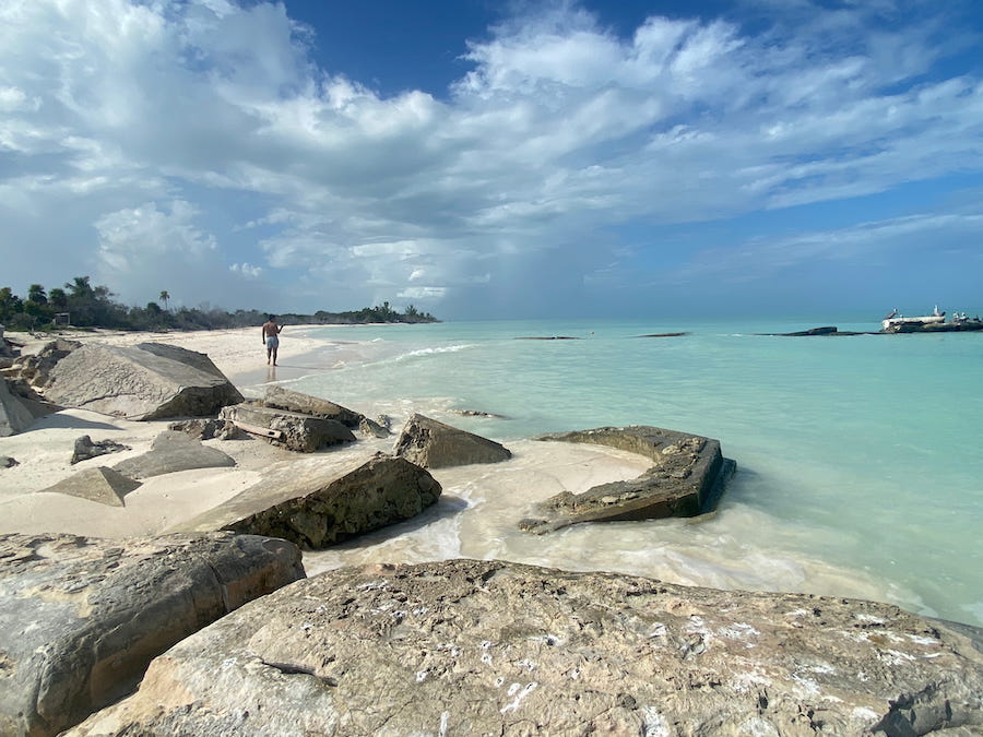 A man in swim trunks photographing pelicans off of Cabot Catoche.