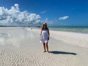 Writer / Photographer Diana Ballon in a sunhat and white sundress on the white sands of the sandbar at Punta Mosquito.