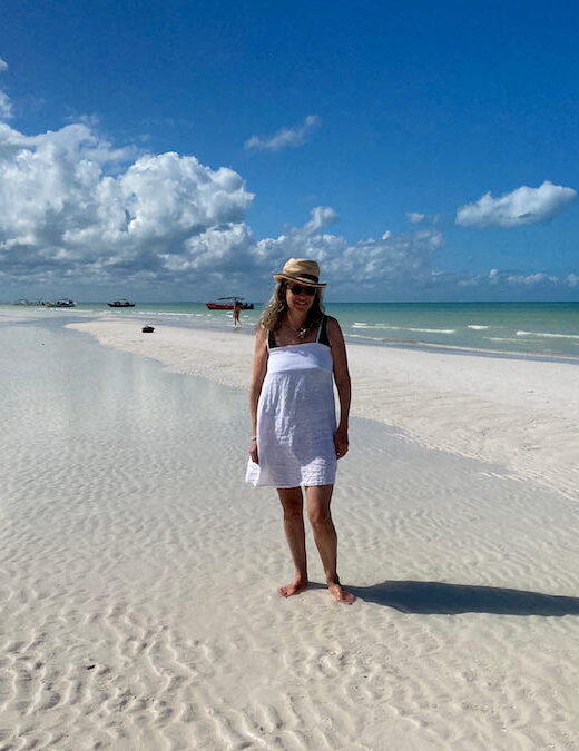 Writer / Photographer Diana Ballon in a sunhat and white sundress on the white sands of the sandbar at Punta Mosquito.