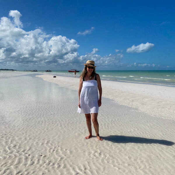 Writer / Photographer Diana Ballon in a sunhat and white sundress on the white sands of the sandbar at Punta Mosquito.