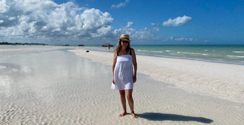 Writer / Photographer Diana Ballon in a sunhat and white sundress on the white sands of the sandbar at Punta Mosquito.