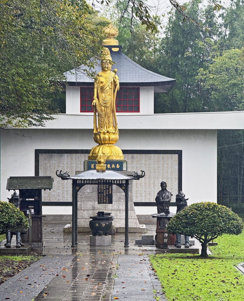 The golden statue of Kannon stands in front of a small temple in Fuji Bussharito Heiwa Park in Gotemba.