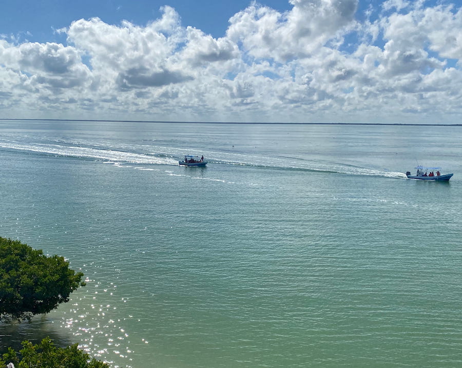 Boats skimming across turquoise waters off of Isla Holbox.