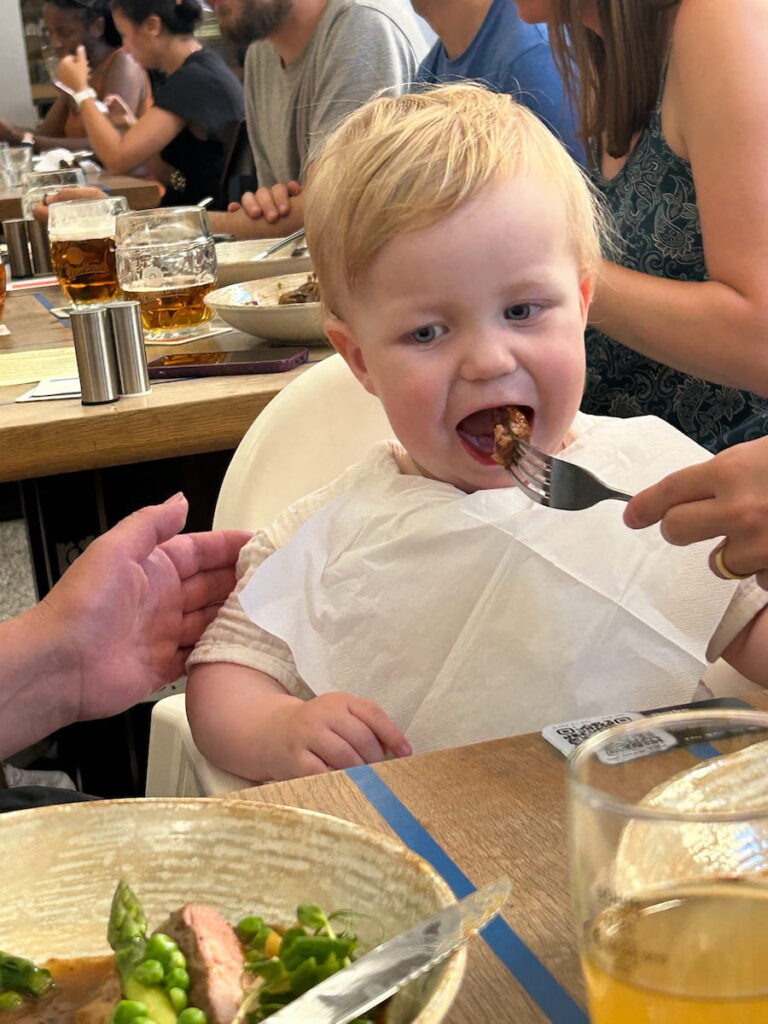 Real baby opening it's mouth for a bite of food, while dining at Vinohradsky Parlament Restaurant.