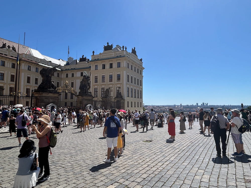 Tourists admiring Schwarzenberg Palace and the view over Prague, Czechia on a sunny summer day.