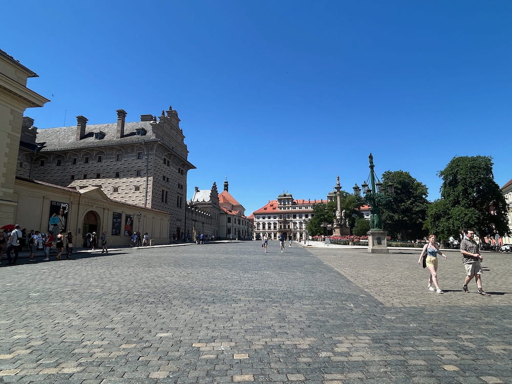 Tourists enjoying a sunny day exploring the grounds of Schwarzenberg Palace in Prague, Czechia.