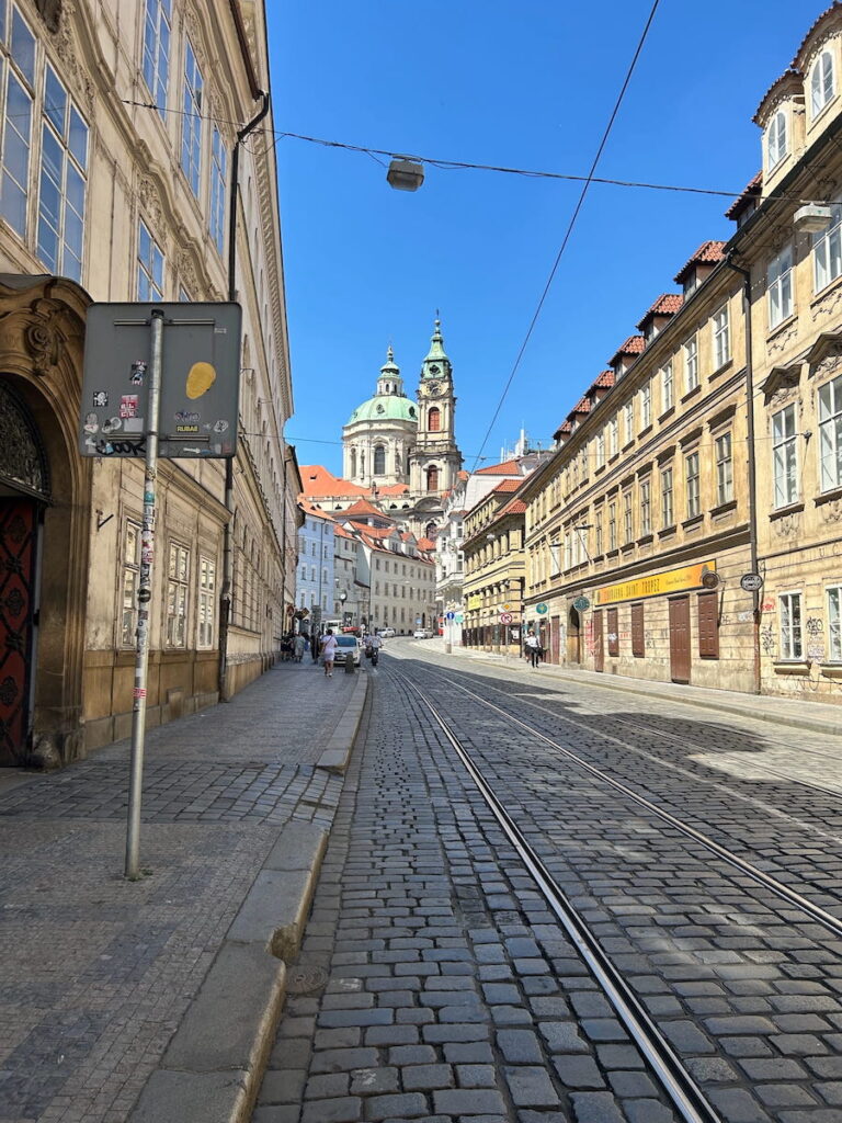 The green domed roofs of St. Nicholas Church down the streets of Prague, Czechia.