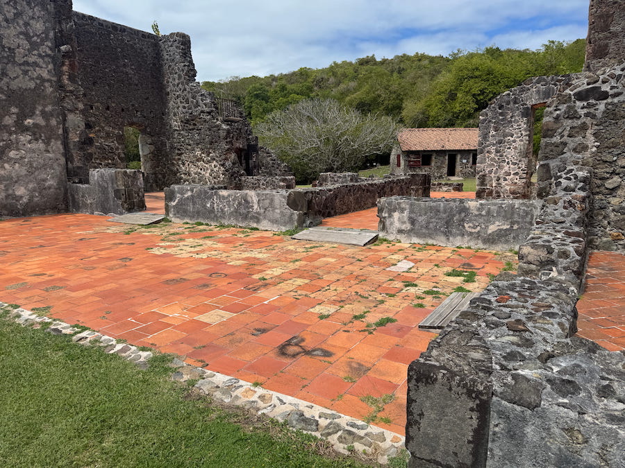 A red brick patio amidst the grey stone ruins of Chateau Dubuc on Martinique.
