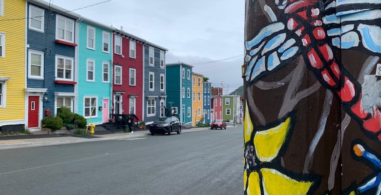 A dragonfly painted telephone post across from the colourfully painted homes of Jellybean Row.