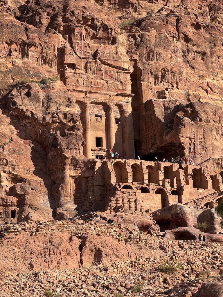 Looking way up above the terrace to see the funerary urn of the Urn Tomb, built into the rose red rock of Petra.